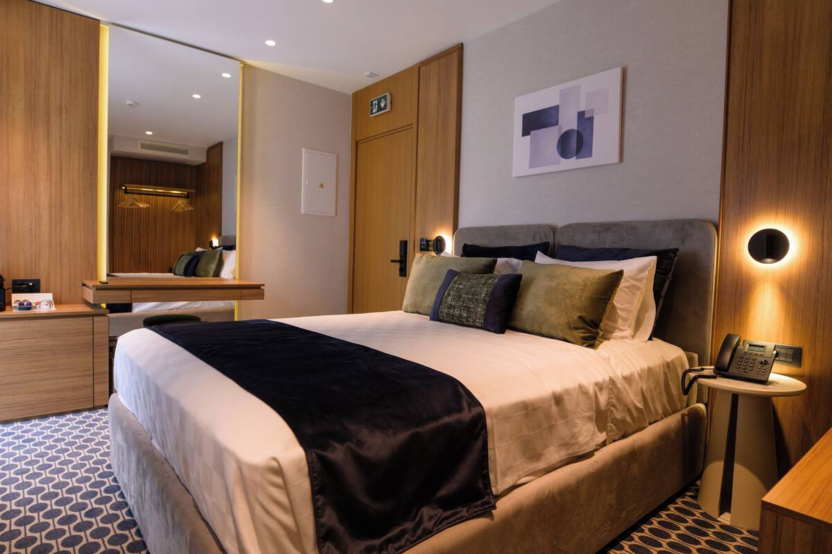 Una habitación de hotel con una cama grande, un escritorio, un espejo y un teléfono en la pared.