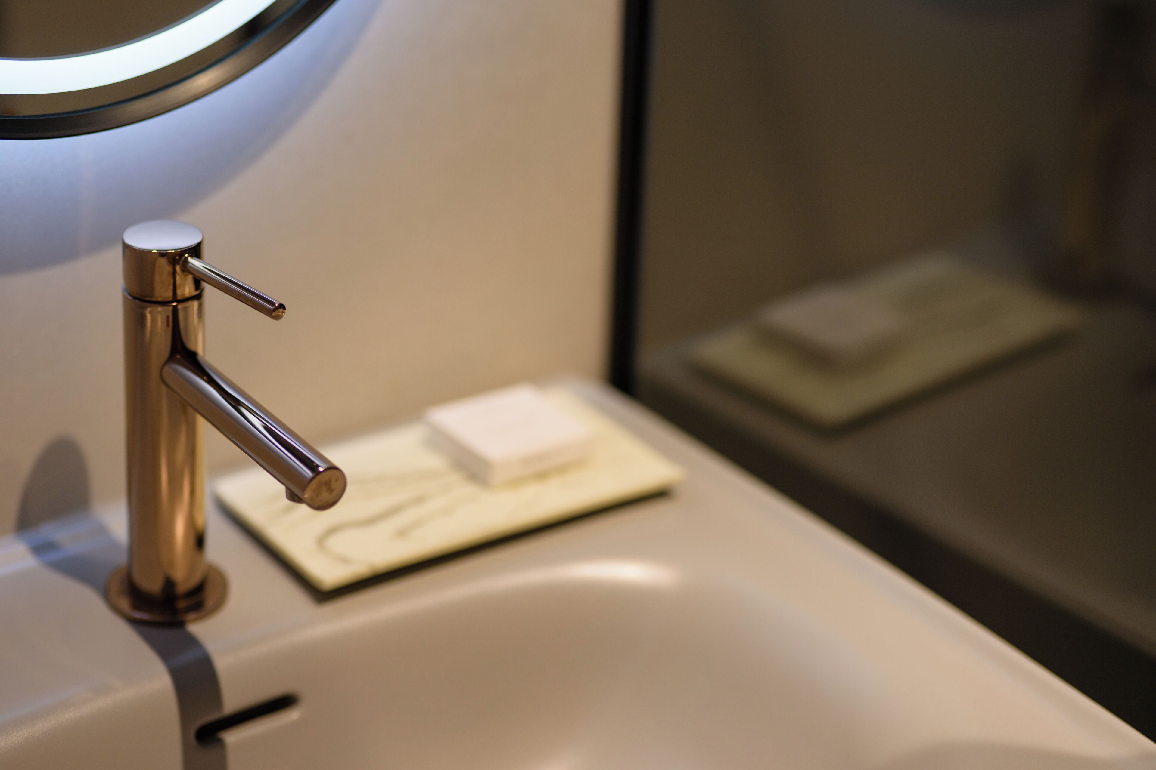 A bathroom sink with a modern faucet, a soap dish, and a mirror above the sink.