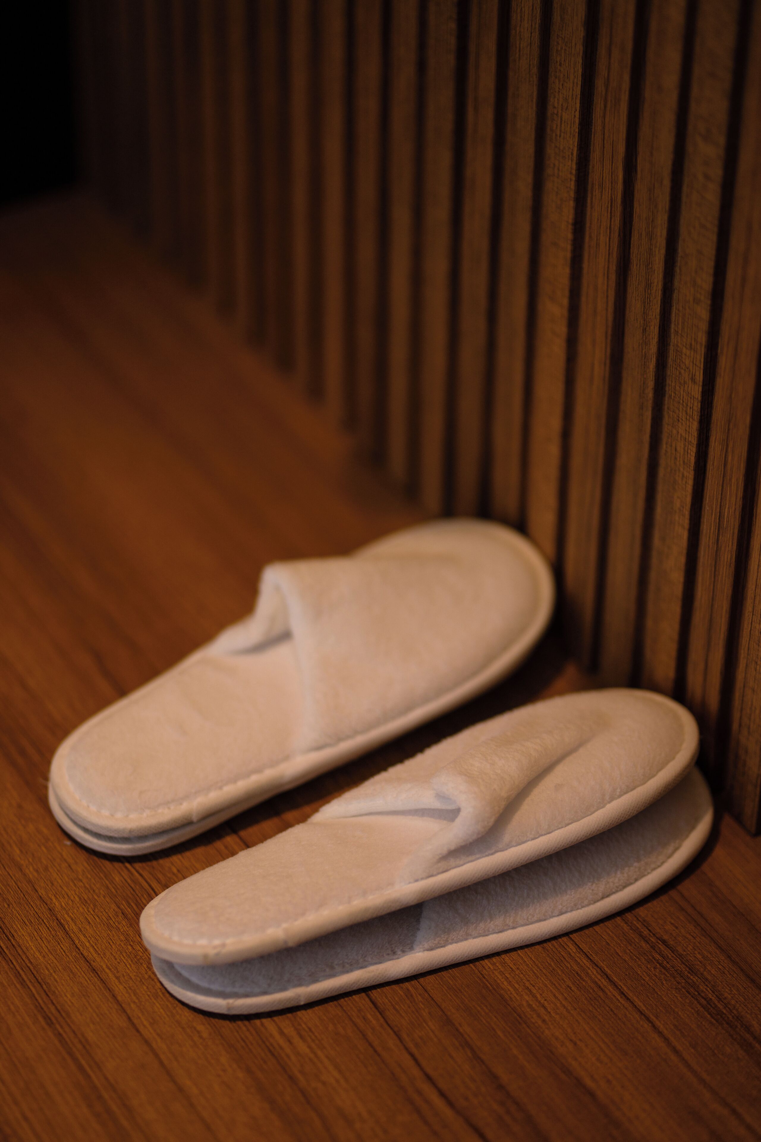 A pair of white slippers on a wooden floor.