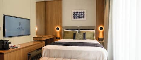 A hotel room with a bed, bedside lamps, a desk, a television, and a wall-mounted artwork.