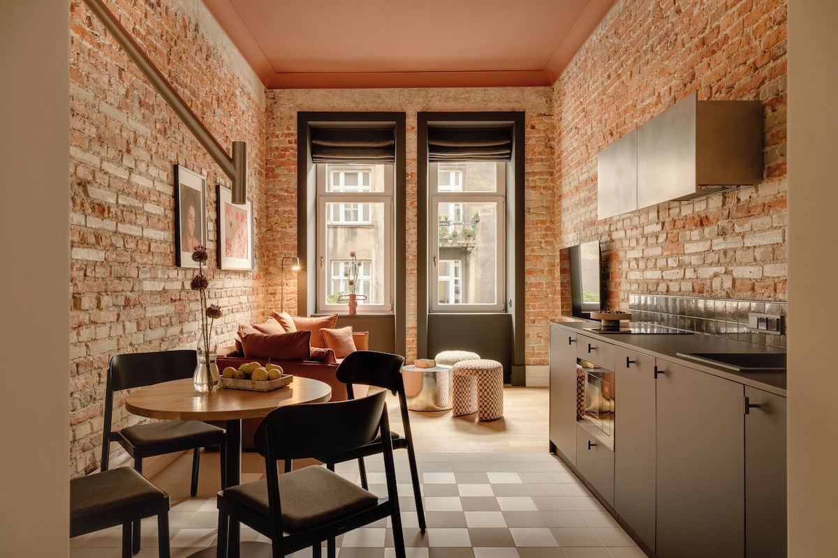 Eine kompakte Küche mit Essbereich, mit freiliegenden Backsteinwänden, einem Schachbrettfußboden und Blick durch die Fenster.