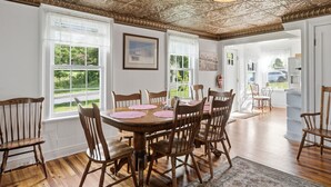 A dining room with a wooden table and chairs, large windows, and a decorative ceiling. - Historic Sugar Loaf Farmhouse | 5BR | Sleeps 8 (Chester)
