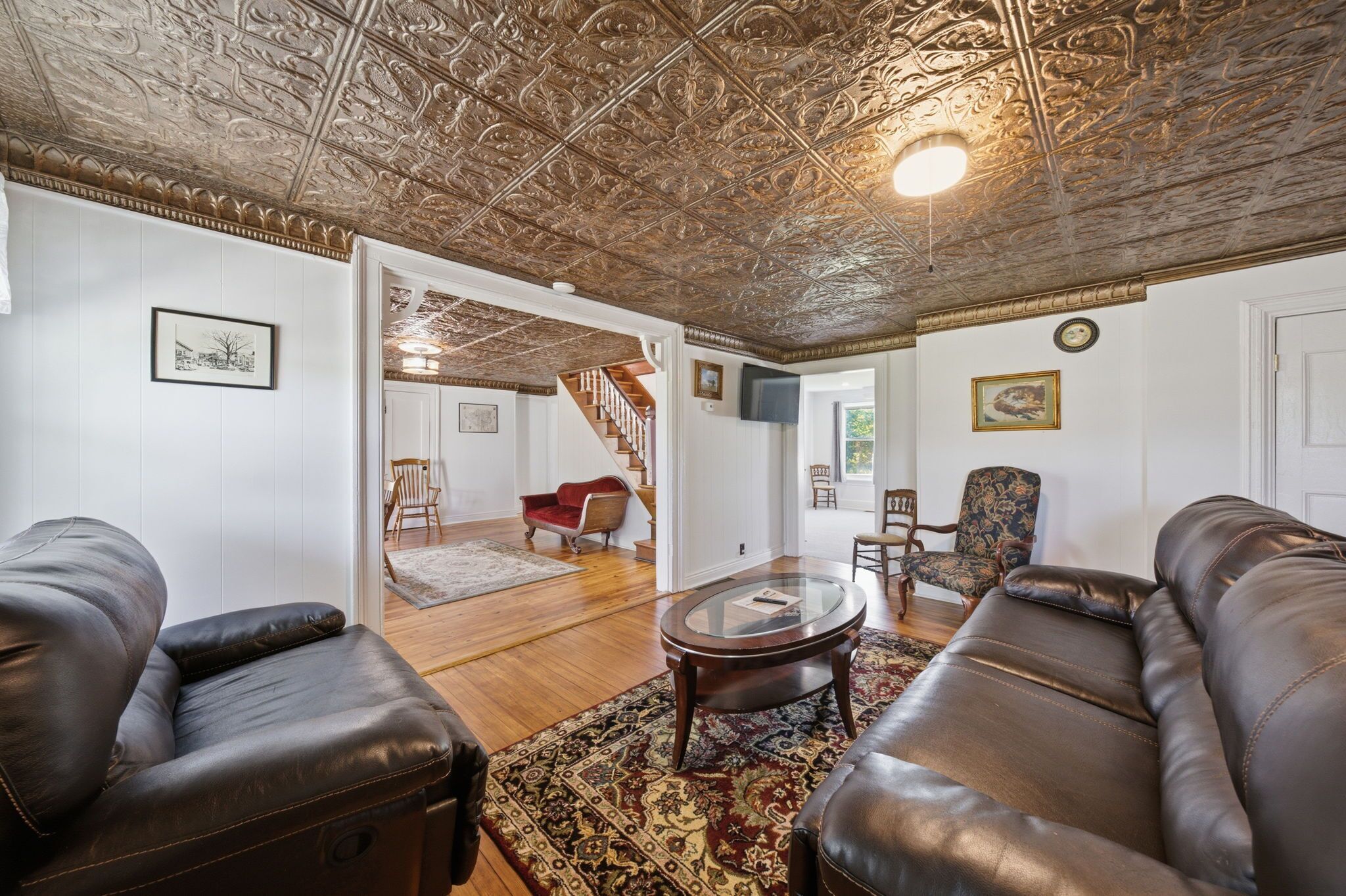 A living room with leather sofas, a glass coffee table, patterned rug, and a decorative ceiling.