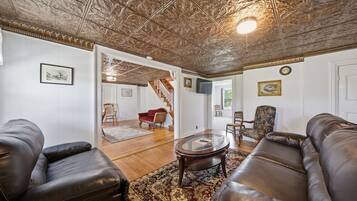 A living room with leather sofas, a glass coffee table, patterned rug, and a decorative ceiling.