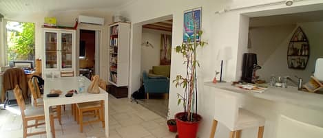 A living room with a dining area, a bookshelf, a potted plant, and a white ceiling.