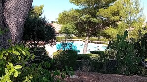 En swimmingpool omgiven av träd och ett inhägnat område.