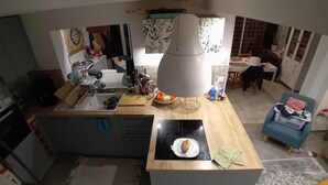 Ett modernt kök med en köksö i mitten, en matplats med bord och stolar samt en blå fåtölj.