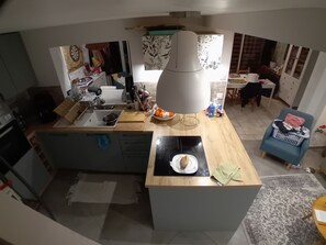 Eine moderne Küche mit einer zentralen Kochinsel, einem Essbereich mit Tisch und Stühlen sowie einem blauen Sessel.