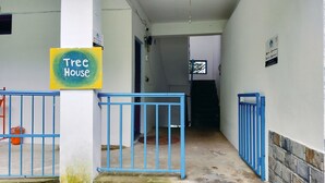 A hallway with a blue gate, a sign reading 'Tree House,' and a wall-mounted sign with text.