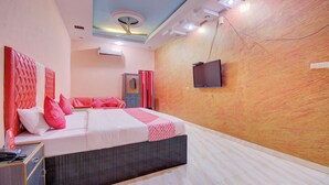 A hotel room with a bed, a wardrobe, a television, and a ceiling fan.