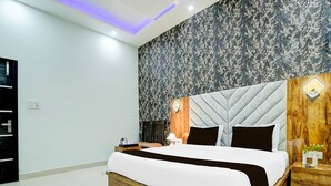 A modern hotel room with a large bed, wooden headboard, and a floral-patterned wall. - Deluxe Chahal Residency (Amritsar)