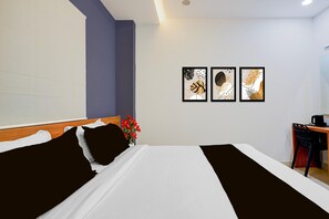 Une chambre d’hôtel avec un lit, un bureau et trois œuvres d’art encadrées accrochées au mur.