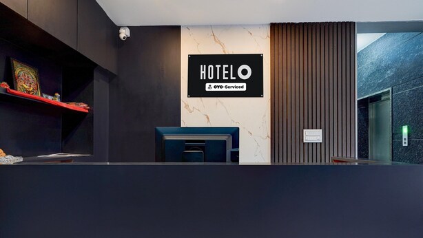 En hotellreception med en skylt som visar att hotellet tillhör OYO-kedjan och följer deras standarder.