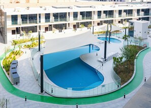 Ein modernes Gebäude mit einem großen, gebogenen Schwimmbecken, umgeben von einem Grünstreifen.