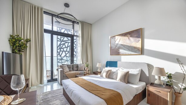 Ein modernes Hotelzimmer mit einem großen Bett, Nachttischen, einem Fernseher und Blick ins Freie.