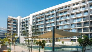 Ein modernes Hotel mit mehreren Etagen, einem zentralen Innenhof mit Pool und einer überdachten Sitzgelegenheit.