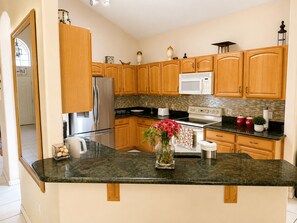 A kitchen with wooden cabinets, stainless steel appliances, a granite countertop, and a vase with flowers.
