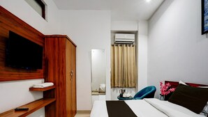 A bedroom with a bed, a TV mounted on the wall, a wardrobe, and an air conditioning unit. - Suite Amritsar District Court (Amritsar)