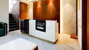 A reception desk with a sign reading 'Collection,' a staircase, and a green sofa. - Suite Amritsar District Court (Amritsar)