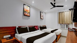 A hotel room with two beds, a ceiling fan, artwork on the walls, an air conditioning unit, and a desk with a telephone. - Suite Amritsar District Court (Amritsar)