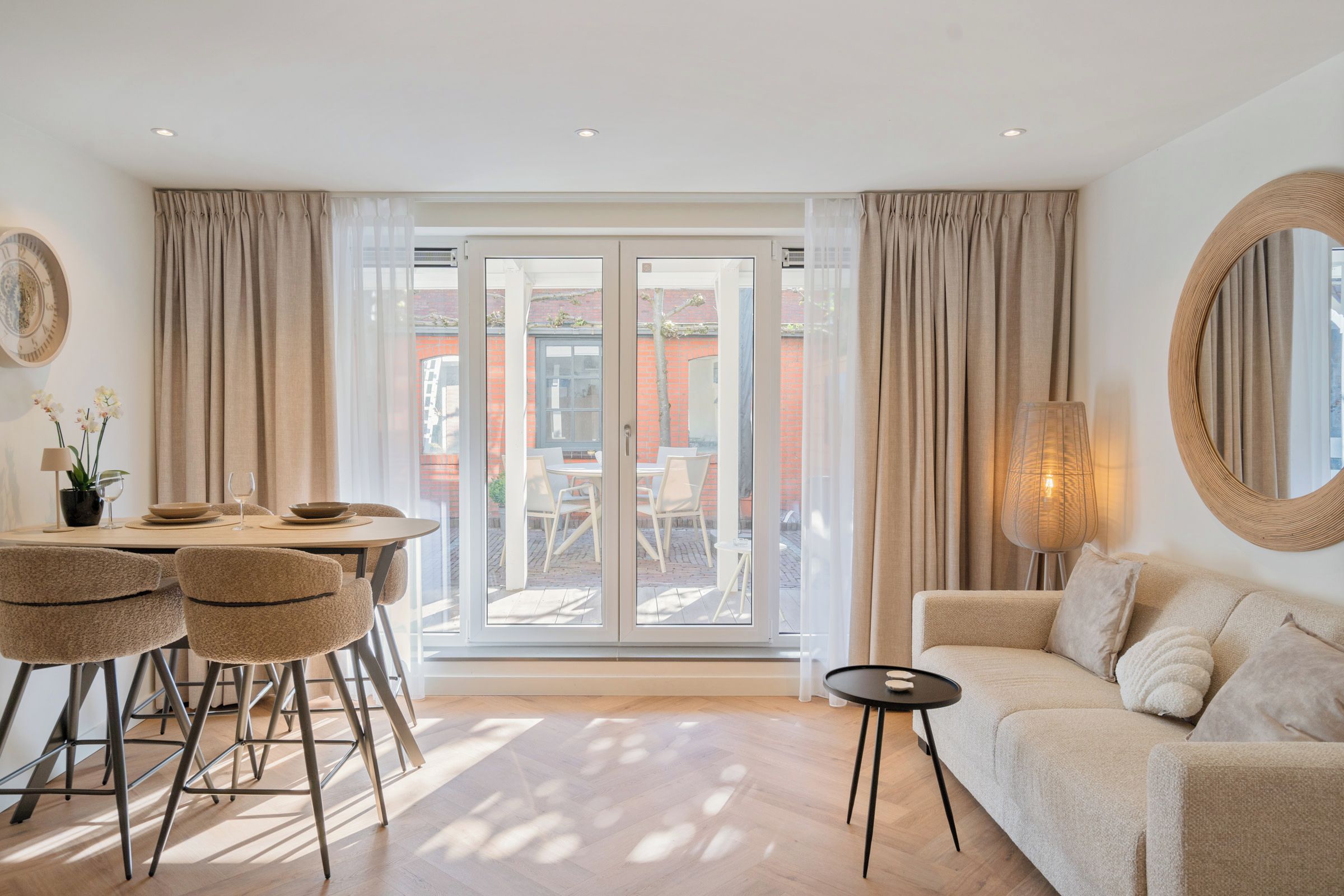 Ein modernes Wohnzimmer mit einer Couch, einem Esstisch mit Stühlen und einer großen Schiebeglastür, die zu einer Terrasse im Freien führt.