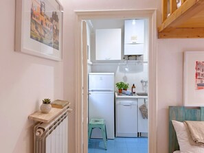 A narrow hallway leading to a compact kitchen with a refrigerator, a dishwasher, and a small stool. - Loft del Cefalo - In the heart of the old town (Roma)