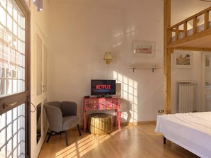A room with a bed, a TV on a pink table, a chair, and a window with blinds. - Loft del Cefalo - In the heart of the old town (Roma)
