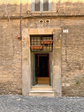 A building with a stone facade, a wooden door, and a small set of steps leading to the entrance. - Loft del Cefalo - In the heart of the old town (Roma)