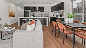 Ein modernes Wohnzimmer mit einer Couch, einem Couchtisch und einem Essbereich mit Stühlen und einem Tisch.