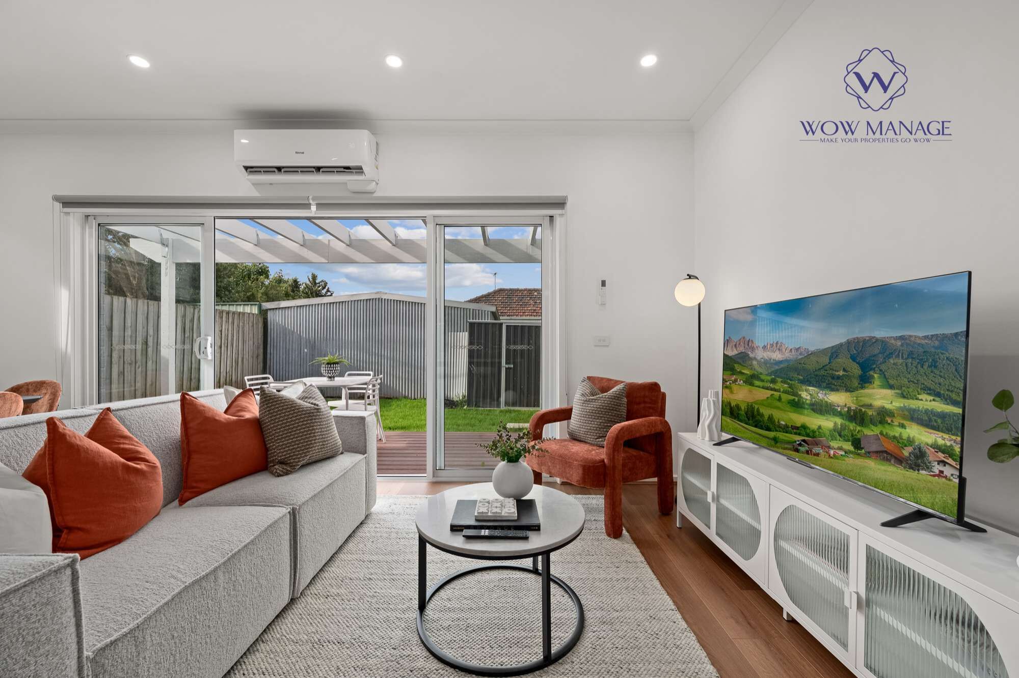 A modern living room with a sofa, armchairs, a coffee table, and a TV.