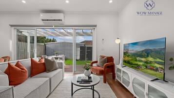 A modern living room with a sofa, armchairs, a coffee table, and a TV.