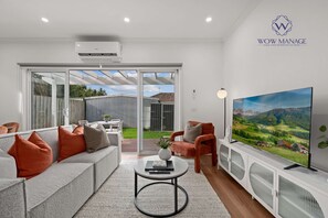 A modern living room with a sofa, armchairs, a coffee table, and a TV. - Relaxing Modern 4B3B Family Home Sleep 8 | Parking (Sunshine)