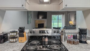 A kitchen with a stainless steel stove, a coffee maker, and various spices.