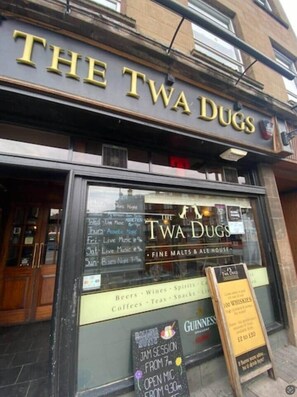 A building with a sign reading 'THE TWA DUGS' and a window displaying a menu. - Mossie Apartment Ayr Town Centre (Ayr)