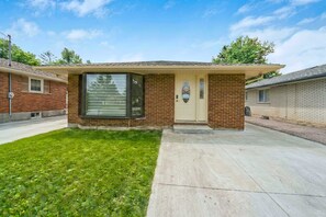 A single-story house with a front garage door, a small front yard, and a clear sky. - Bright Basement Suite w Parking Near Mclennan Park (Kitchener)