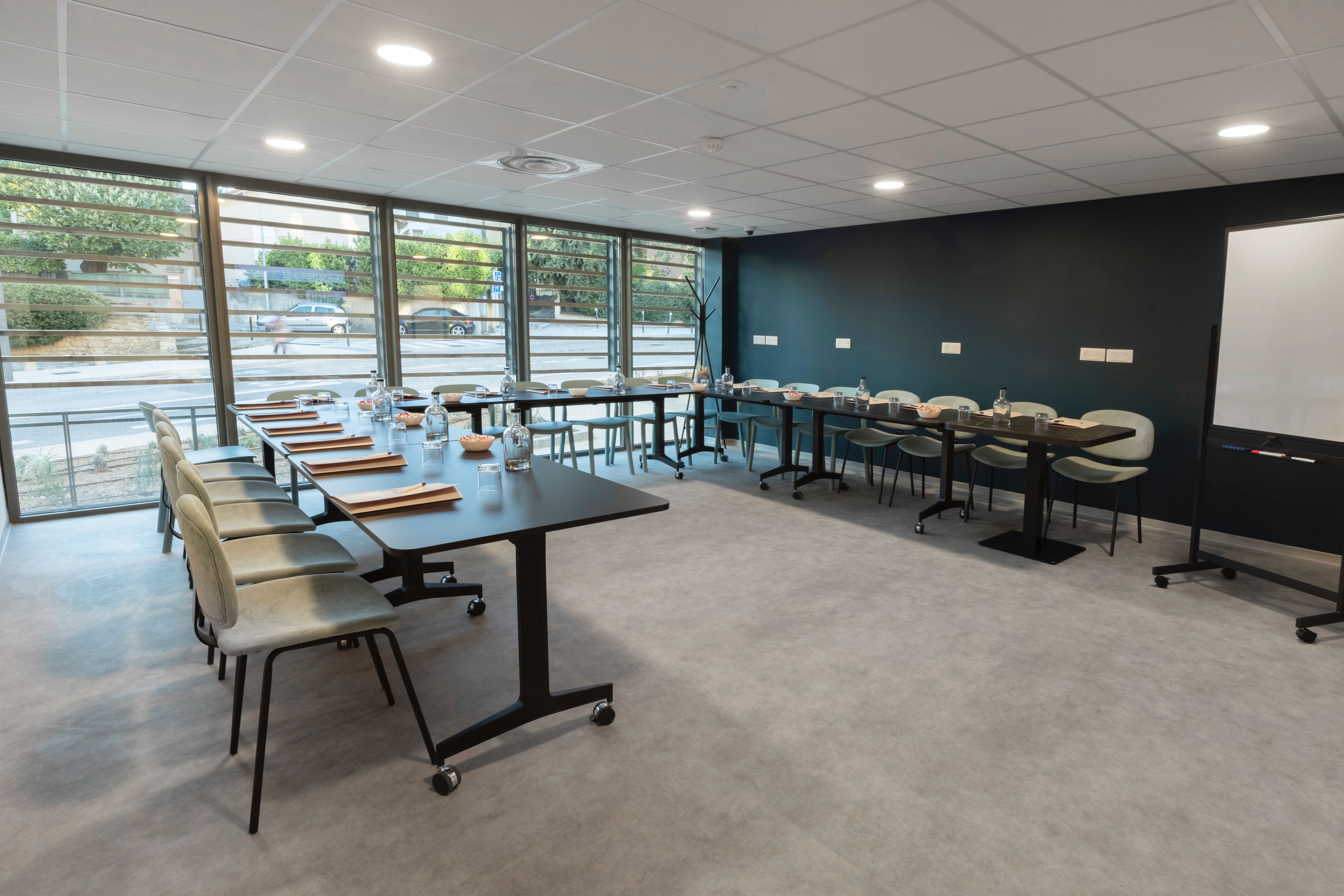 A conference room with a long table, chairs, and a projector screen.