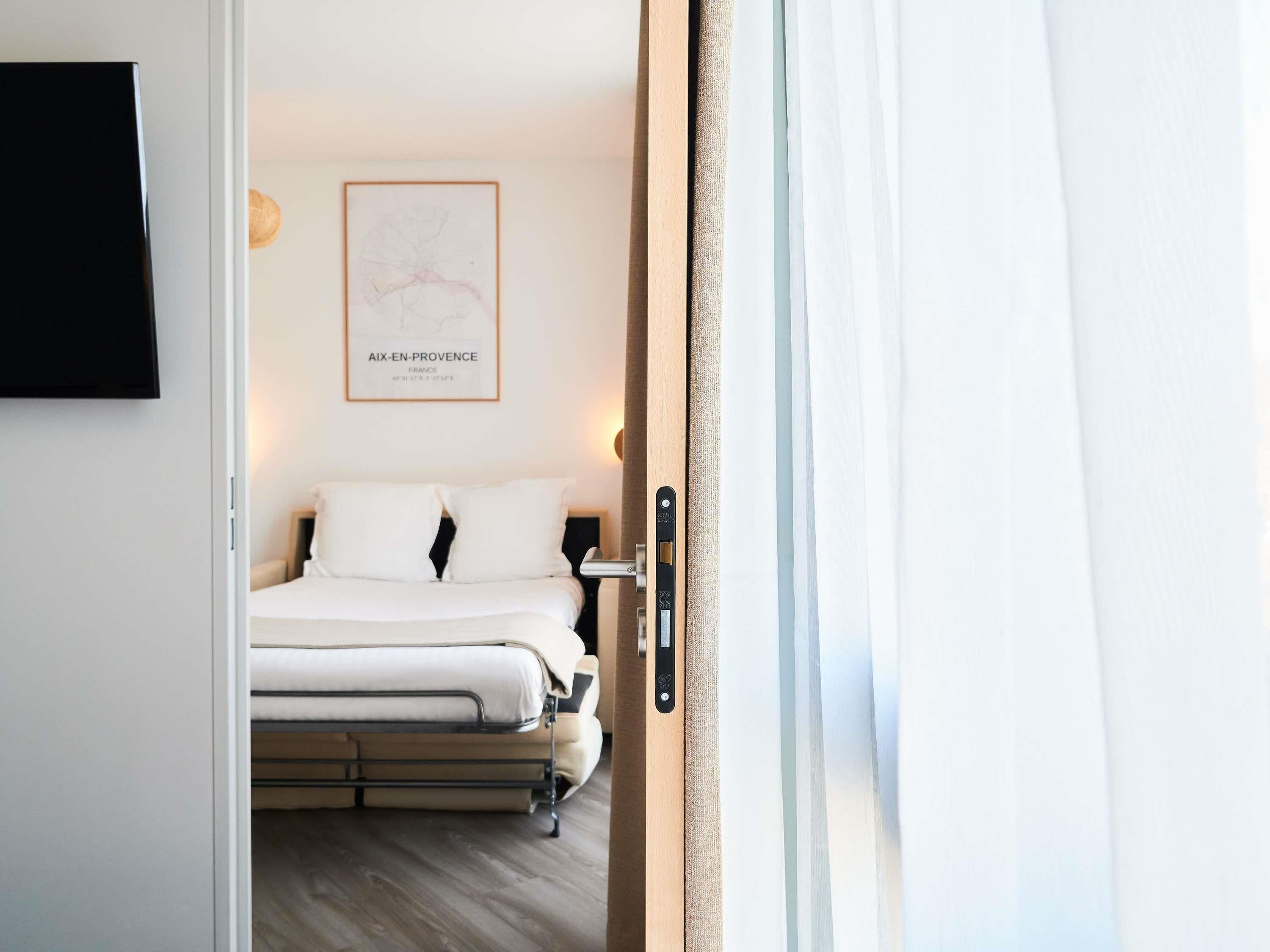 Habitación de hotel con cama, televisor montado en la pared y un mapa enmarcado.