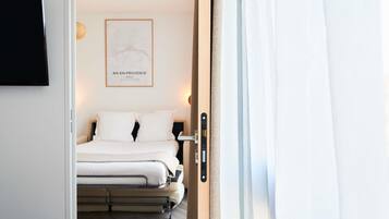 Habitación de hotel con cama, televisor montado en la pared y un mapa enmarcado.