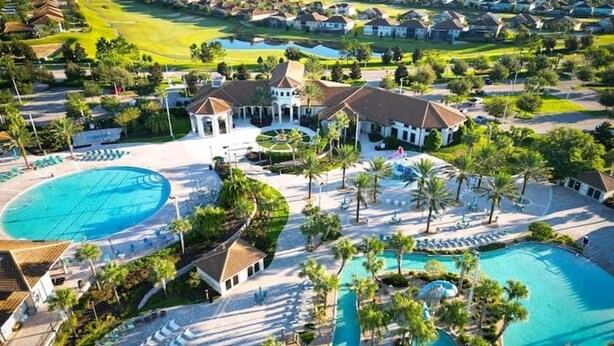 Ein Resort mit mehreren Schwimmpools, Palmen und einem Golfplatz im Hintergrund.