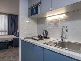 Cocina compacta equipada con microondas, hervidor y lavabo.