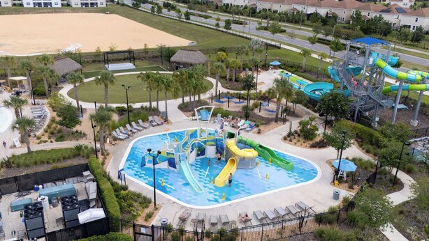 An aerial view of a water park with multiple slides and pools, surrounded by palm trees and lounge areas. - ChampionsGate 5BR | Pool, Xbox + Oasis Resort (Davenport)