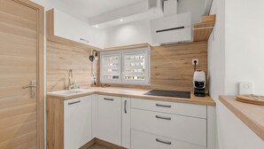 A modern kitchen with white cabinets, a wooden countertop, a built-in window, and a coffee machine. - Apartment Horizon Bleu by Sur la mer (Les Issambres)