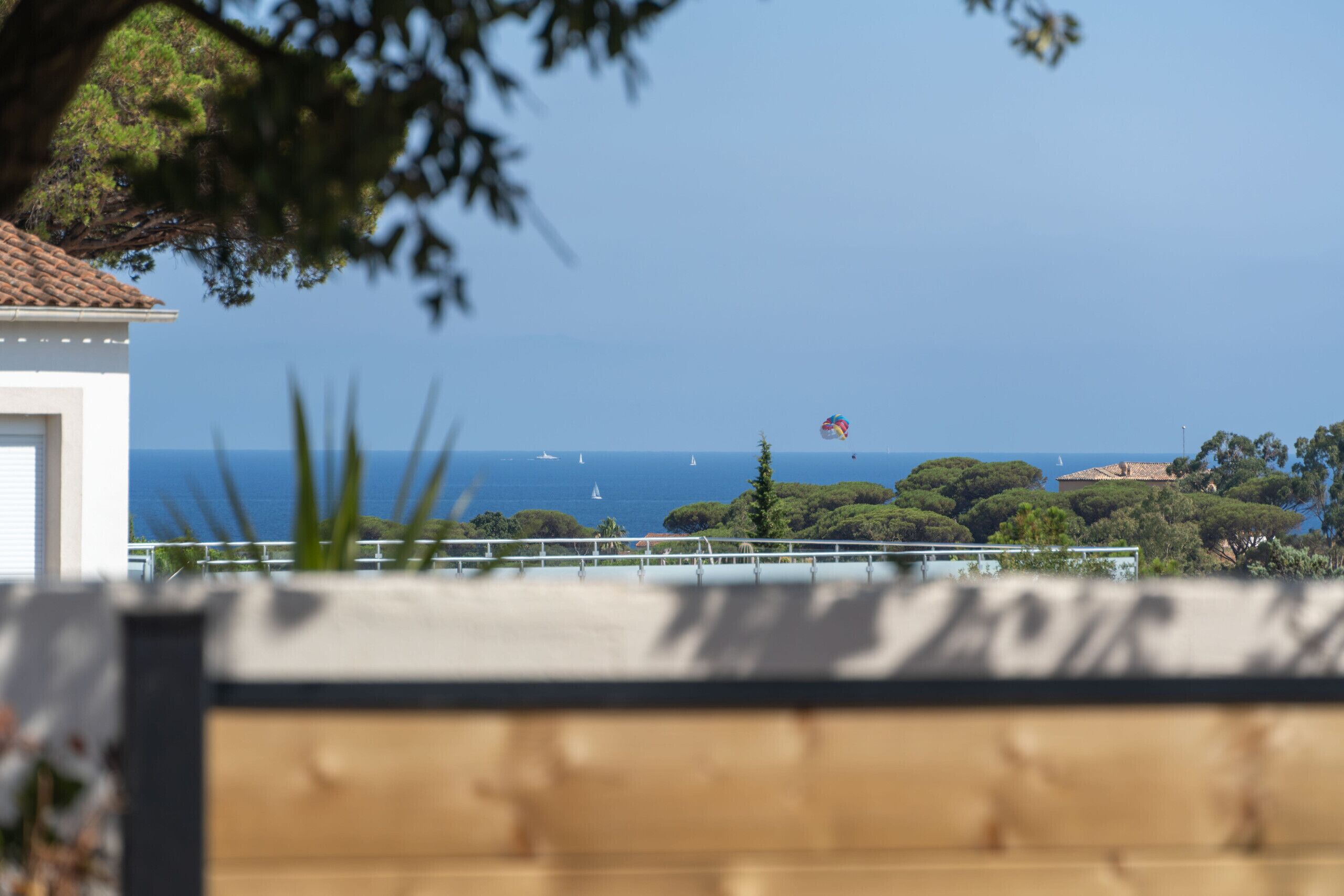 A coastal view with a clear sky, a sailboat, and a hot air balloon.