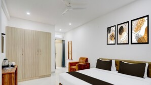 Une chambre d’hôtel comprenant un lit, une armoire, un bureau, une chaise et des œuvres d’art accrochées au mur.