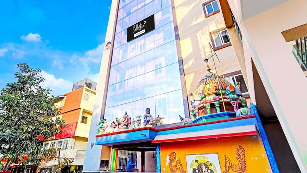 Un hôtel doté d’une façade moderne en verre, d’une entrée colorée ornée de statues et d’une enseigne indiquant le nom « Collector ».