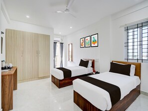 A hotel room with two beds, a wardrobe, a desk, and a window with blinds. - Classic With Balcony Bangalore Inn (Bengaluru)
