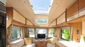 A compact RV interior with a central bed, a small kitchenette, and a skylight. - Rod and Rest (Chulmleigh)