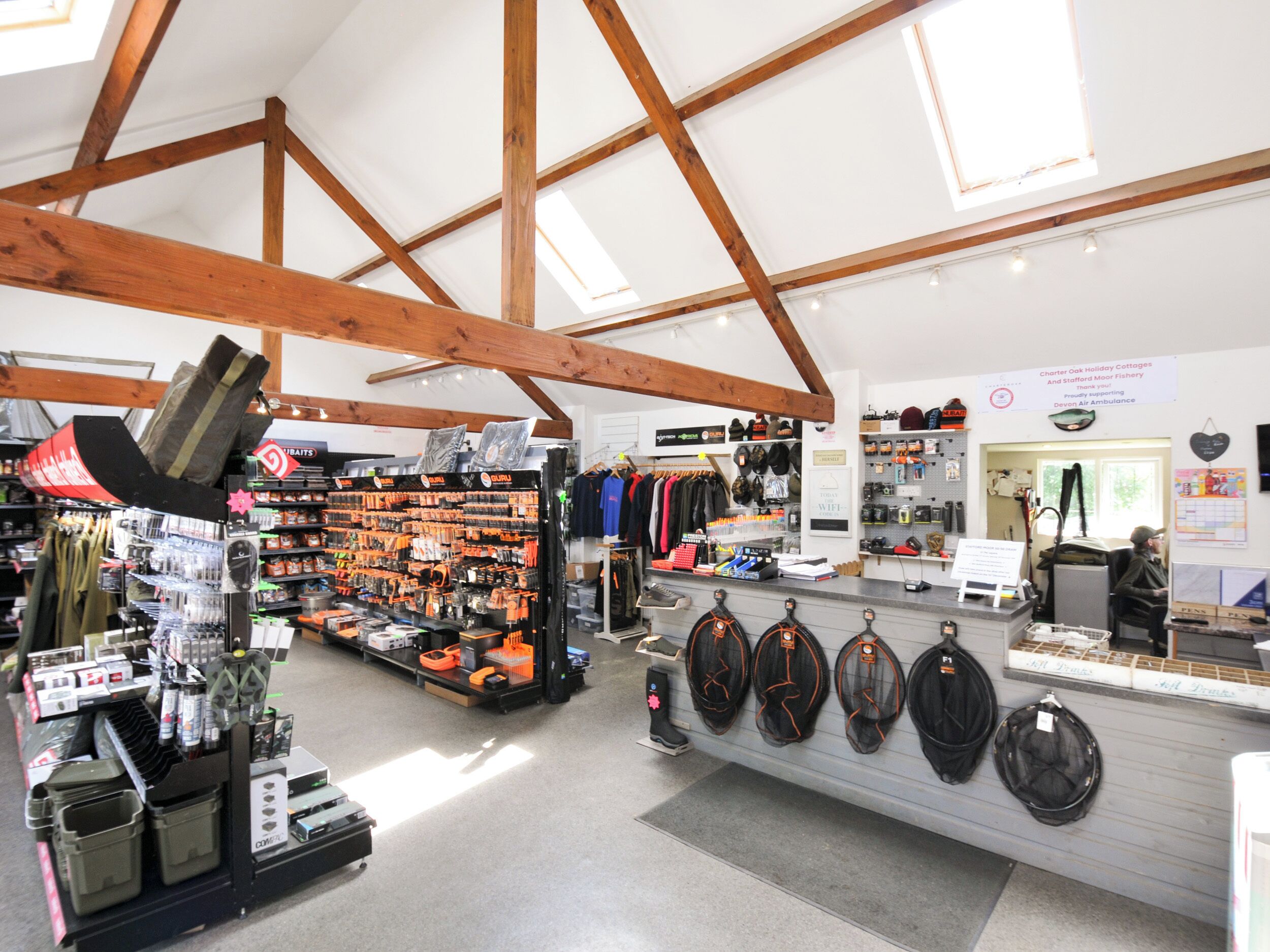 A store with wooden beams, shelves stocked with fishing gear, and a counter with hats.