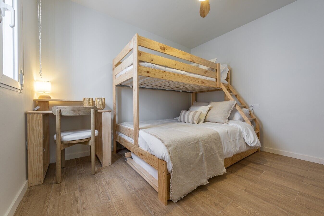 Een stapelbed met bureau, stoel, lamp en een trap.