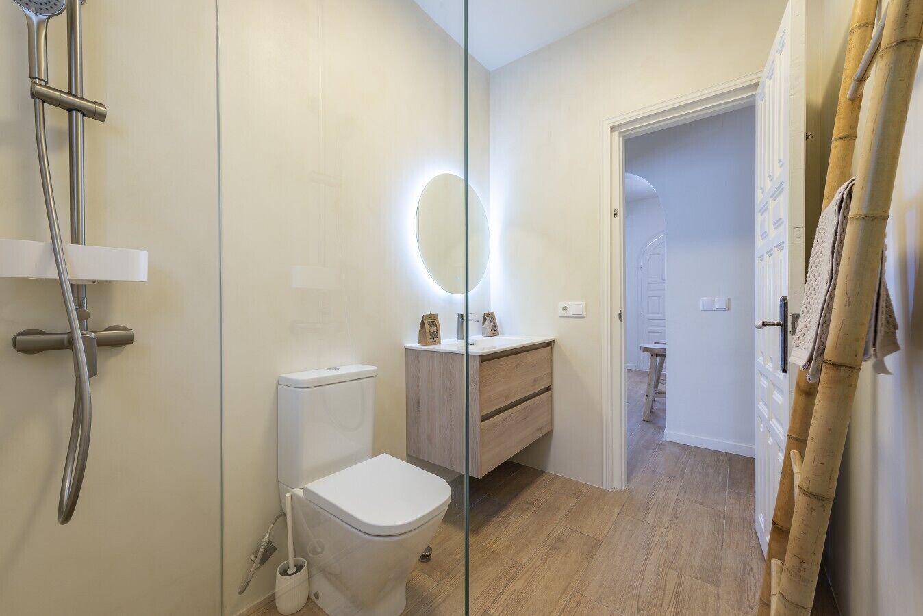 A bathroom with a toilet, a shower, a mirror, and a wooden vanity.